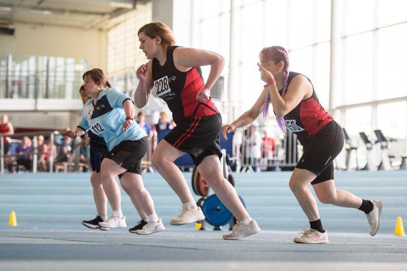Photo of four Special Olympics GB athletes start to run a race at an indoor event